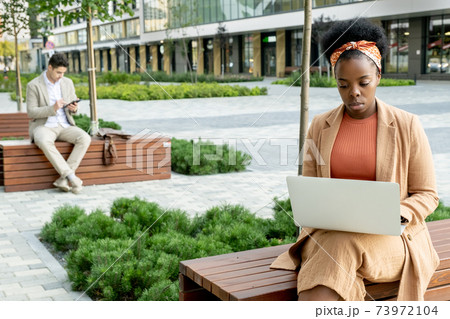 Woman working online outdoors Woman working online outdoors 73972104