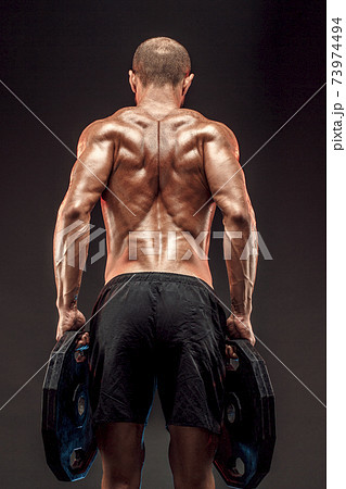 Muscled shirtless male model showing his back muscles on dark background isolate 73974494