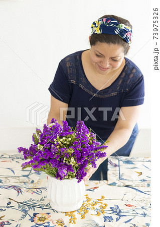 Pretty woman decorating her home table with a beautiful flower arrangement 73975326