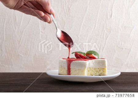 Cheesecake is poured over with berry syrup. Delicate dessert garnished with fresh strawberries. 73977658