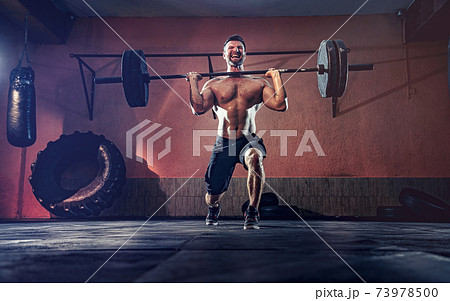 Muscular fitness man doing barbell lunges in his garage, selfisolation. Functional training. Snatch exercise 73978500