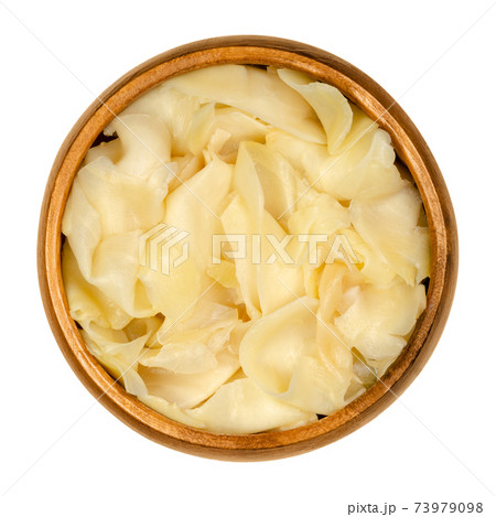 Gari, pickled ginger in a wooden bowl. Thinly sliced ginger, marinated in sugar and vinegar, served after sushi. Traditionally prepared the color is pale yellow or pink. Closeup from above food photo. 73979098