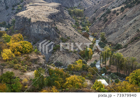 Basalt columns in the gorge of Garni with the mountain river Azat clogged with huge stone boulders Basalt columns in the gorge of Garni with the mountain river Azat clogged with huge stone boulders 73979940