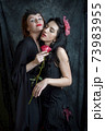 Two women are intoxicated by the fragrance of a red rose Two women are intoxicated by the fragrance of a red rose 73983955