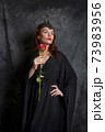 Woman in black dress with red rose Woman in black dress with red rose 73983956
