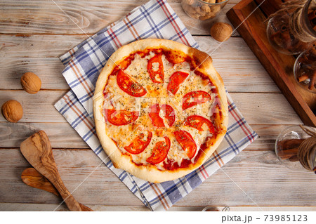 Margherita pizza with tomatoes on the wooden table Margherita pizza with tomatoes on the wooden table 73985123
