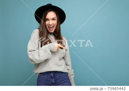 Photo of pretty brunette positive young woman directing finger to the side with empty space 73985442