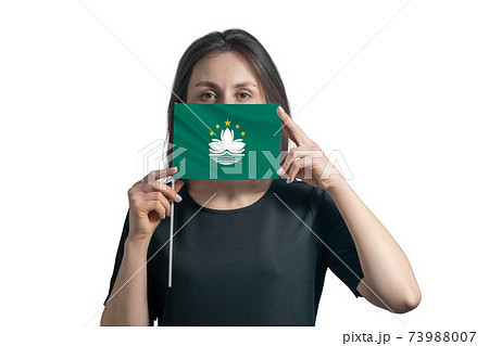Happy young white woman holding flag Macau flag and covers her face with it isolated on a white background Happy young white woman holding flag Macau flag and covers her face with it isolated on a white background 73988007