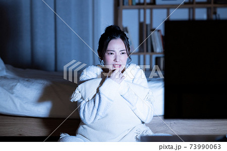 夜のホラー映画を見る若い女性 73990063