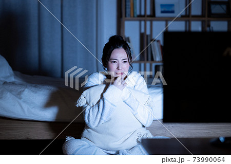 夜のホラー映画を見る若い女性の写真素材