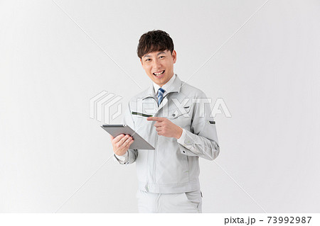 白バックのタブレットを見ながら説明をする笑顔の若い作業員 白バックのタブレットを見ながら説明をする笑顔の若い作業員 73992987