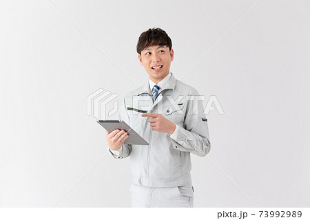 白バックのタブレットを見ながら話をする若い作業員 73992989