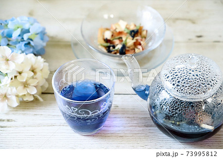 ガラスのティーポットにバタフライピーの青いハーブティーの写真素材