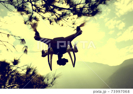 White drone with camera flying in winter tropical mountains 73997068