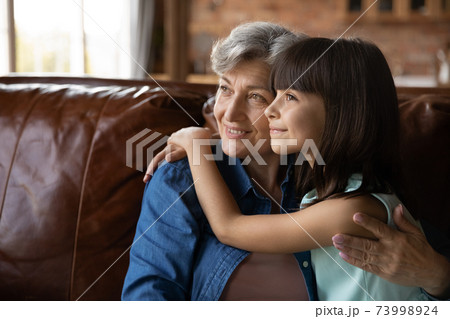 Close up dreamy mature woman and little girl hugging 73998924
