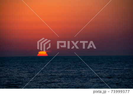 水平線に沈むくびれた夕陽 73999377