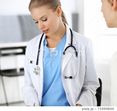 Woman - doctor consults her female patient while using clipboard and medication history record. Medicine concept Woman - doctor consults her female patient while using clipboard and medication history record. Medicine concept 73999600
