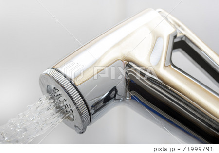 A chrome bidet shower spraying water, close up. The head of the toilet bidet. A chrome bidet shower spraying water, close up. The head of the toilet bidet. 73999791