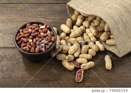 Peanuts in shell and peeled peanuts in a bowl on a wooden table. Beer snacks. Healthy food concept. 74000154