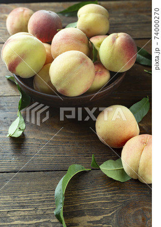 Fresh harvest of peaches in a clay bowl on a wooden rustic table. Fresh harvest of peaches in a clay bowl on a wooden rustic table. 74000270
