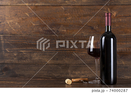 Bottle of wine and glasse. There is a corkscrew and a cork nearby. Bottle of wine and glasse. There is a corkscrew and a cork nearby. 74000287