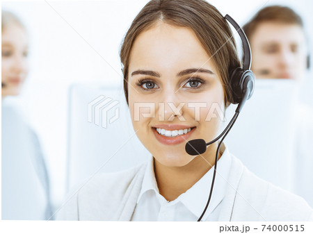 Call center. Group of diverse operators at work. Beautiful woman in headset communicating with customers of telemarketing service. Business concept Call center. Group of diverse operators at work. Beautiful woman in headset communicating with customers of telemarketing service. Business concept 74000515