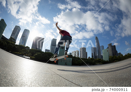 Asian woman skateboarder skateboarding in modern city Asian woman skateboarder skateboarding in modern city 74000911