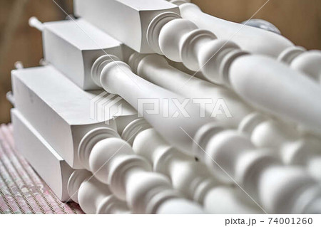 White balusters. Balusters process production. Solid wood balusters before finishing. Furniture manufacture. Close-up White balusters. Balusters process production. Solid wood balusters before finishing. Furniture manufacture. Close-up 74001260
