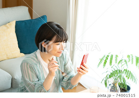 スマホを見ながら食事をする女性 スマホを見ながら食事をする女性 74001515