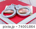 Handcuffs and money on the book. Criminal penalty for fraud 74001864