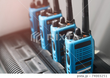 A set of blue walkie-talkies stand in a row. A device for transmitting stable radio communication 74003251