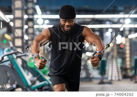 Motivated black sportsman having workout on crossover machine 74004202