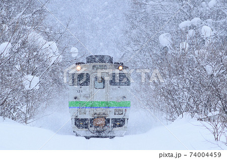 林の中の雪路を往く石北本線の普通列車 74004459