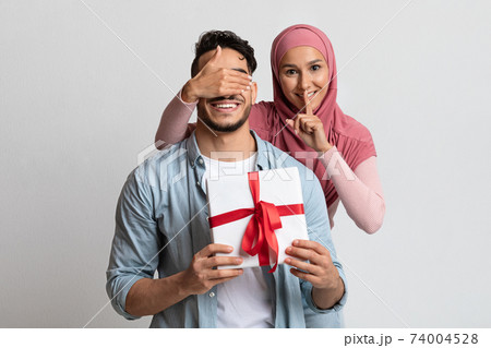 Surprise Gift. Romantic Muslim Woman Covering Her Husband's Eyes And Giving Present 74004528