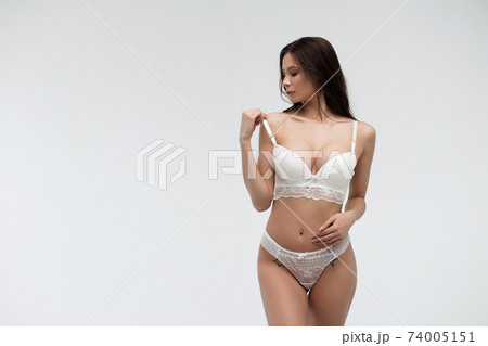 Hot sexy woman in white lace lingerie looking at camera touching body 74005151
