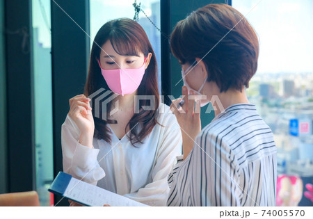 シェアオフィスでミーティングするマスクをした若いビジネスウーマン 74005570