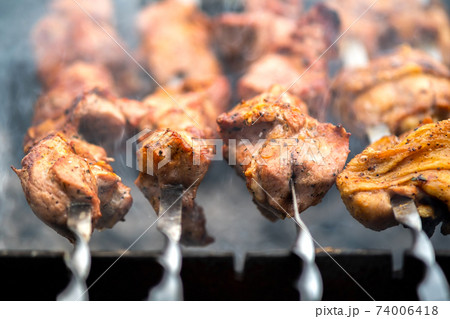 Shashlik or shish kebab preparing on barbecue grill over hot charcoal. Grilled pieces of pork meat on metal skewers. Shashlik or shish kebab preparing on barbecue grill over hot charcoal. Grilled pieces of pork meat on metal skewers. 74006418