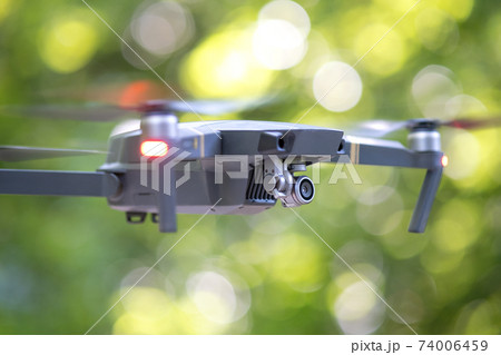 Drone copter with blurred propellers and video camera flying in air. 74006459