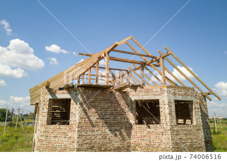 Aerial view of unfinished house with wooden roof frame structure under construction. Aerial view of unfinished house with wooden roof frame structure under construction. 74006516