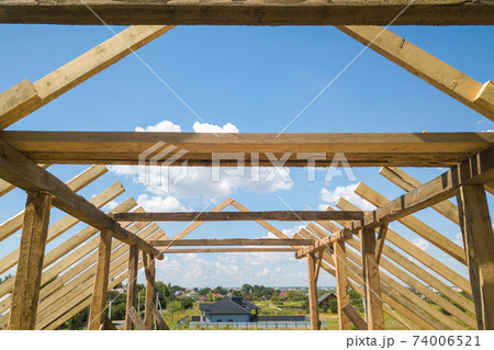 Aerial view of unfinished house with wooden roof frame structure under construction. 74006521