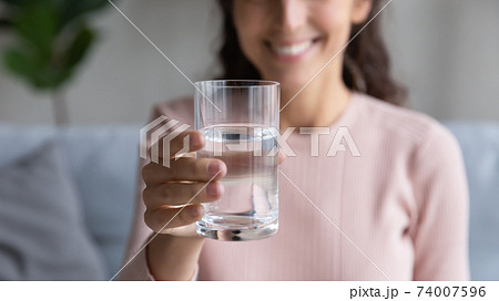 Close up glass with mineral clean water in female hands. Close up glass with mineral clean water in female hands. 74007596