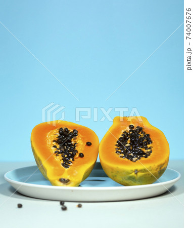 Two Half of Papaya with Green and Seeds on Blue Background, Minimalism Trendy Food, Healthy and Detox Eating, Raw lunch, Vertical Copyspace, Exotic Fruit Two Half of Papaya with Green and Seeds on Blue Background, Minimalism Trendy Food, Healthy and Detox Eating, Raw lunch, Vertical Copyspace, Exotic Fruit 74007676