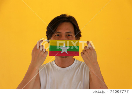 A man with Myanmar flag on hygienic mask in his hand and lifted up the front face A man with Myanmar flag on hygienic mask in his hand and lifted up the front face 74007777