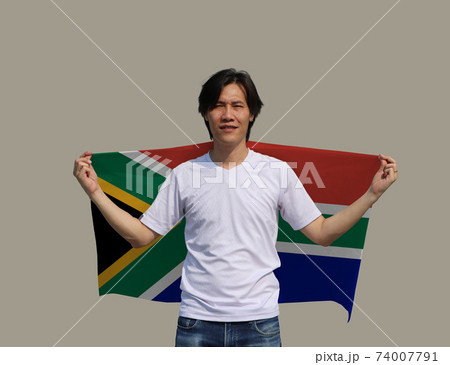 The man holding South Africa fabric flag on his shoulder on grey background. The man holding South Africa fabric flag on his shoulder on grey background. 74007791