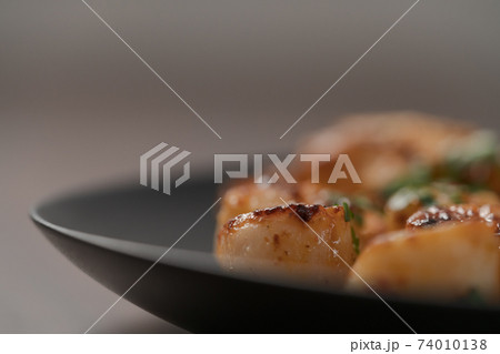 Seared scallops on black plate closeup Seared scallops on black plate closeup 74010138