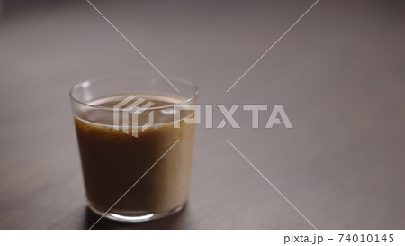 milk pour into tumbler glass with coffee on walnut table 74010145