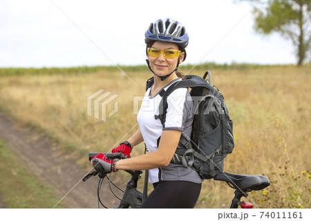 Beautiful woman cyclist with a bicycle on the nature. Healthy lifestyle and sport.  74011161