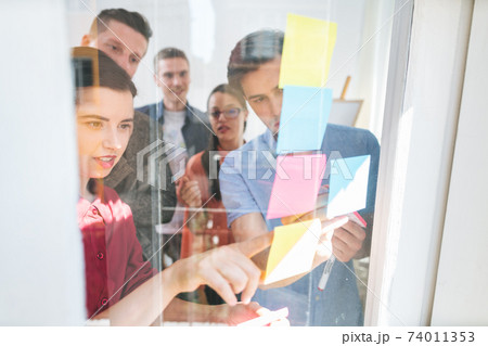 Office team looking at sticky notes Office team looking at sticky notes 74011353