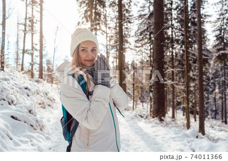 Woman on winter hike enjoying the sunset in the forest Woman on winter hike enjoying the sunset in the forest 74011366