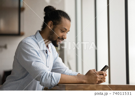 Positive young black male having pleasure playing game by cell 74011531